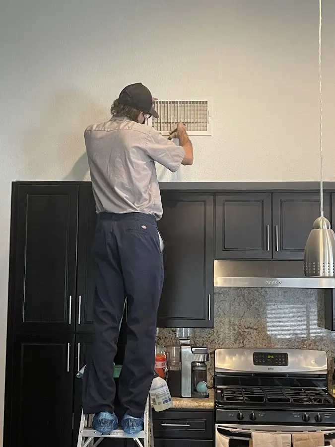Technician inspecting an air vent during HVAC service in Helena Valley Northwest